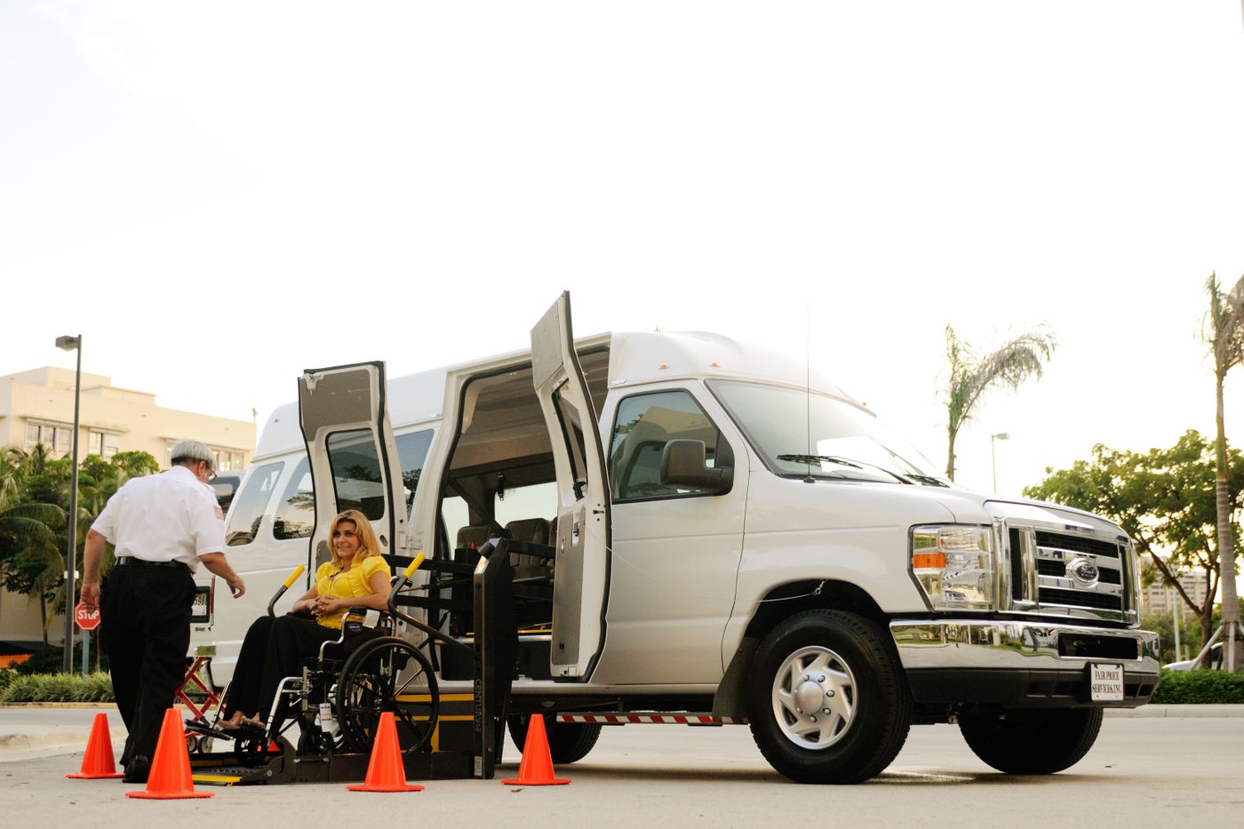A driver helping a rider onto an accessible van lift