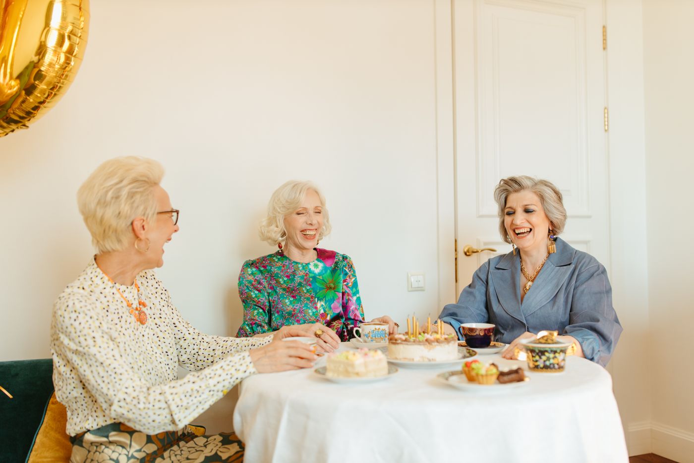 Three women laughing together over tea